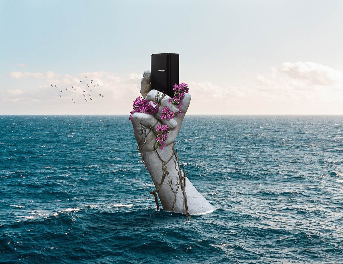 A hand holding a smartphone above the water